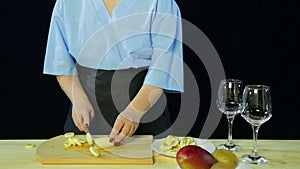 Woman cook on a black background slices bann on a wooden board