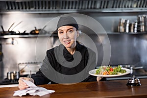 Woman cook checks paid check and cooked dish in kitchen