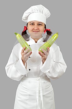 The woman the cook holds green vegetable marrows.