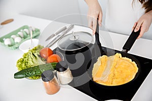 Woman cook an omelette on the pan.