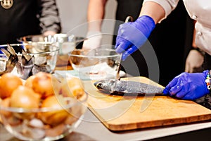 Woman cook preparing and cleaning raw dorada fish
