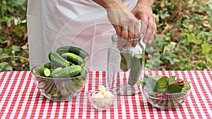 Woman cook puts cucumbers for preservation in an empty glass jar