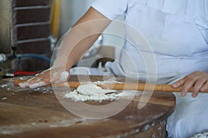 A woman cook, in the traditional manual way, bakes a Turkish gozleme cake in an old oven. Preparation of dough, kneading