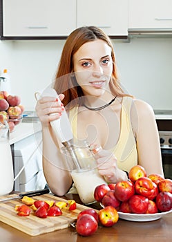 Woman cooking beverages from nectarines and milk at kitchen