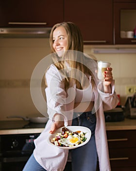 Woman cooking breakfast on her kitchen at home. Focus on tthe Eggs on her plate