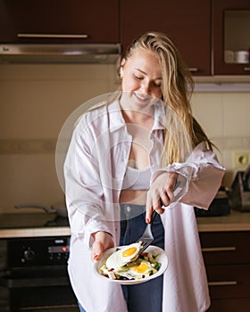 Woman cooking breakfast on her kitchen at home. Focus on tthe Eggs on her plate