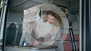 Woman cooking camper van at morning close up. Happy curly lady prepare breakfast