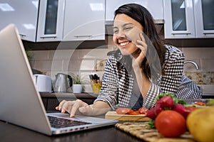 woman cooking checking recipe at laptop