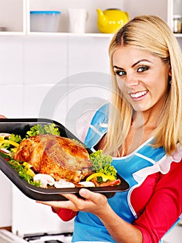 Woman cooking chicken at kitchen.