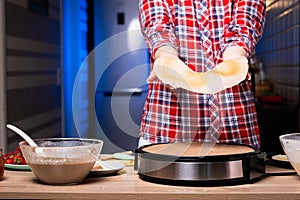 Woman cooking delicious crepe on electric pancake maker in kitchen, closeup