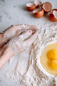 Woman cooking dough. Chicken eggs in flour on the kitchen table, ingredients