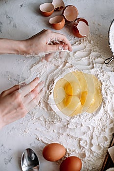 Woman cooking dough. Chicken eggs in flour on the kitchen table, ingredients
