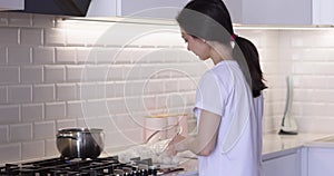 woman cooking dumpling in boiling water in kitchen