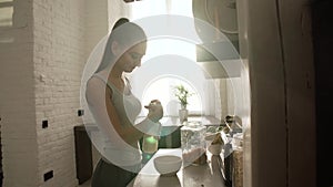 Woman cooking flakes with milk for breakfast at light kitchen