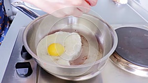 Woman cooking fried eggs on steel frying pan