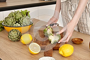 Woman cooking green artichokes in the kitchen