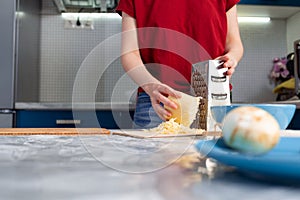 Woman cooking in the kitchen, grating cheese. Hands close-up. The concept of a home-cooked meal