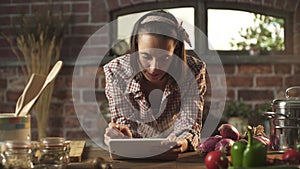 Woman cooking in the kitchen and using a digital tablet