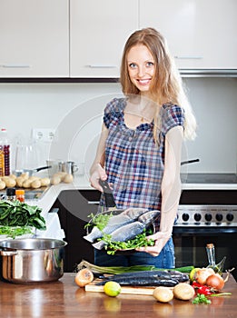 Woman cooking lubina fish in frying pan photo
