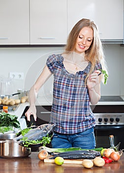 Woman cooking lubina fish in fryingpan