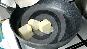 Woman cooking melting butter on frying pan mixing with wooden spatula.