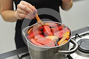 Woman cooking mulled wine at the kitchen