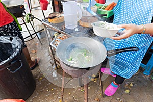 Woman Cooking Noodle Soup Outdoors On Traditional Street Market In Asia Food Preparing On Open Bazaar