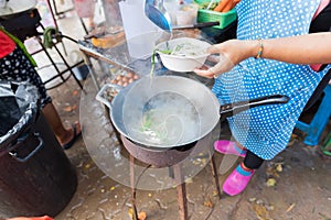 Woman Cooking Noodle Soup Outdoors On Traditional Street Market In Asia Food Preparing On Open Bazaar
