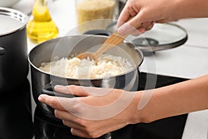Woman cooking rice on stove in kitchen, closeup