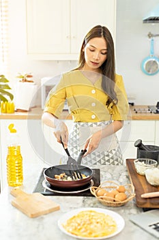 Woman cooking rice with vegetables in kitchen