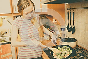 Woman cooking stir fry frozen vegetable on pan