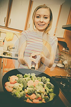 Woman cooking stir fry frozen vegetable on pan