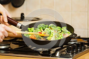 Woman cooking stir fry frozen vegetable on pan