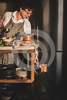 Woman cooking Turkish traditional meat soup Haslama and touching cat