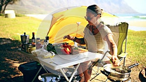 Woman, cooking and vegetables outdoor with camping, sunshine or preparing food in nature with tent. Person, camper or