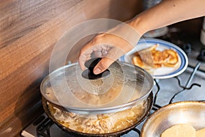 A woman cooks food in a frying pan.
