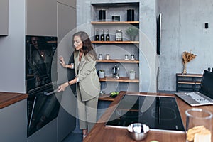 Woman cooks food in the oven and peeks to see if it is ready.