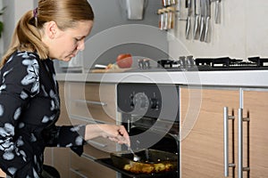 Woman cooks potatoes in the oven