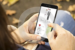 woman with cool wedding invitation design phone in the park