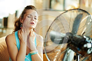 Woman cooling down in front of fan suffering from summer heat