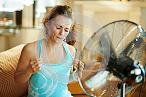 Woman cooling down using fan suffering from summer heat