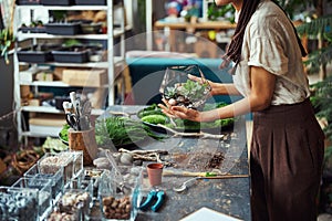 Woman with cornrows holding a polyhedron florarium with both hands