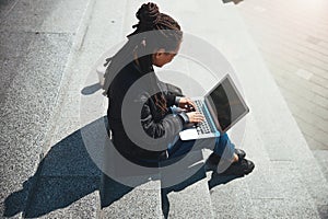 Woman with cornrows typing an email message on her gadget