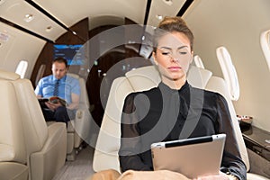 Woman in corporate jet looking at tablet computer