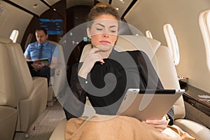 Woman in corporate jet looking at tablet computer