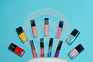 Woman cosmetic bag, make up beauty products on blue background. Red, pink, magenta and blue lipsticks. Set of red, pink, green and