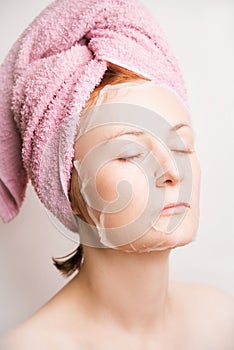 Woman with cosmetic mask anti-wrinkle on face on light background