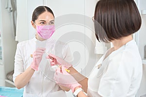 Woman cosmetologist holds a syringe with fillers and a patch