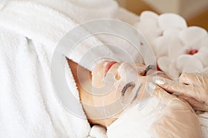 Woman with cotton face mask in beauty salon