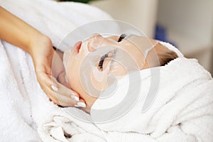 Woman with cotton face mask in beauty salon